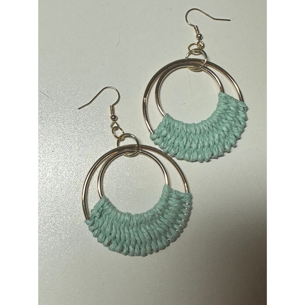 A pair of gold hoop earrings with a woven green fabric detail.